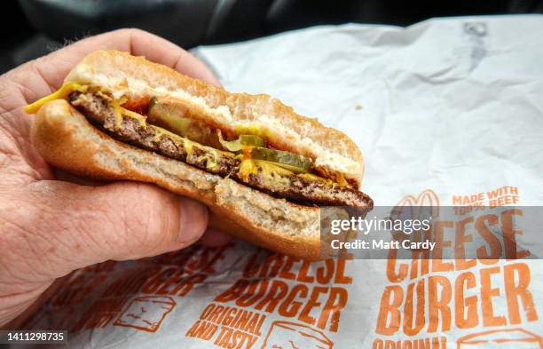 Man eats a McDonald's cheeseburger on July 27, 2022 in Bristol, England. McDonald’s has announced that the price of a cheeseburger will increase for...