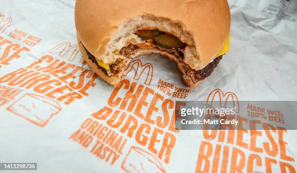 Man eats a McDonald's cheeseburger on July 27, 2022 in Bristol, England. McDonald’s has announced that the price of a cheeseburger will increase for...