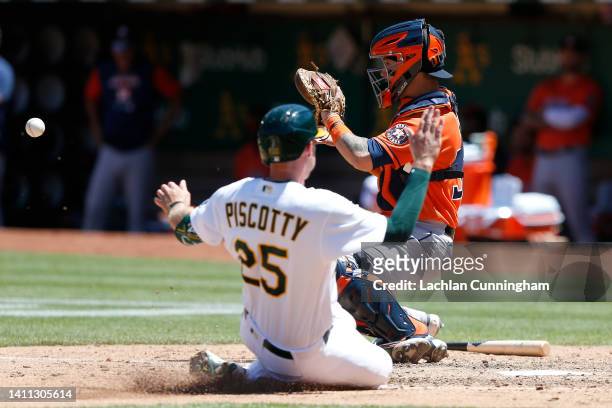 Stephen Piscotty of the Oakland Athletics slides in safe at home plate ahead of the tag by catcher Korey Lee of the Houston Astros to score on a...