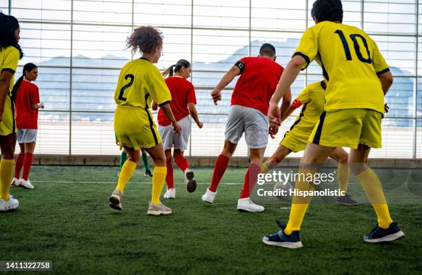 co-ed team of soccer players playing at an indoor field - soccer competition stock pictures, royalty-free photos & images