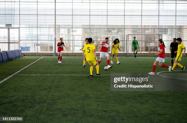 equipo mixto de jugadores de fútbol que juegan en un campo cubierto - liga de futbol fotografías e imágenes de stock