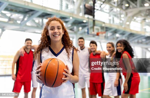 feliz jugadora liderando un equipo de baloncesto y sosteniendo una pelota - strip fotografías e imágenes de stock