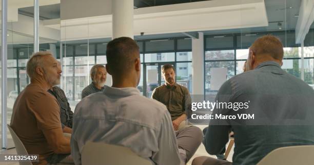 group of men sitting on chairs during a counseling session. therapy to support male patients in addiction to help share and talk about problems in a circle at rehab. businessmen having a debate - cross section stock pictures, royalty-free photos & images
