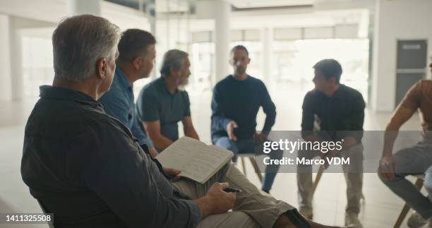 professional psychologist taking notes in a group therapy session in an office. diverse men with mental health issues talk about their feelings and emotions while supporting one another in recovery - team talk stockfoto's en -beelden