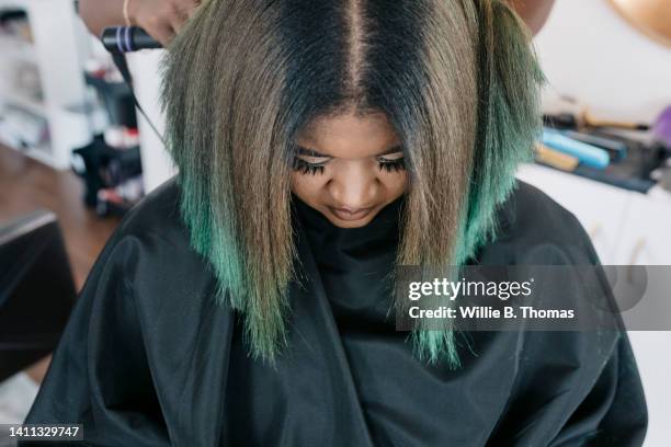 close up of black woman getting hair straightened in salon - straight hair stock pictures, royalty-free photos & images