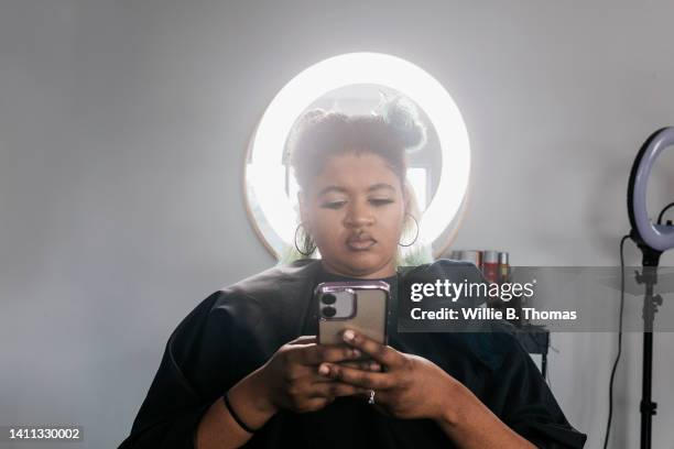 black woman with hair in curlers waiting in salon - hair curlers stockfoto's en -beelden