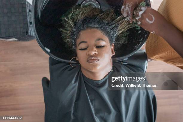 overhead view of black woman having hair washed at salon - femme shampoing photos et images de collection