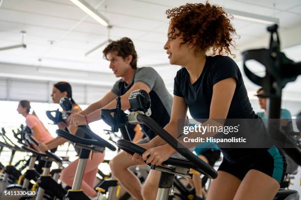 group of fit people working out in a exercising class - stationary cycling class stock pictures, royalty-free photos & images