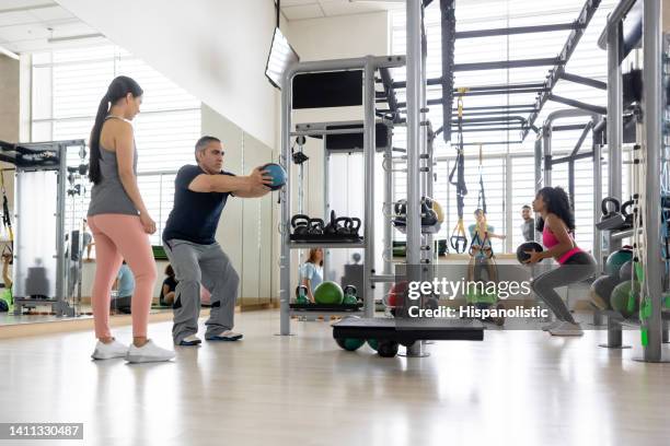 fitness instructor guiding a man exercising at the gym - obesity trainer stock pictures, royalty-free photos & images