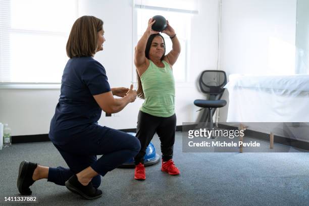 physiotherapist performing techniques with a female client with dwarfism - dwarf stockfoto's en -beelden