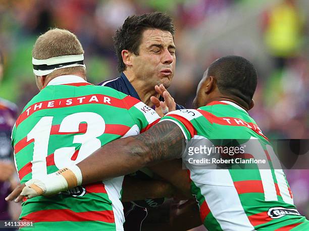 Cooper Cronk of the Storm is tackled by Michael Crocker and Roy Asotasi of the Rabbitohs during the round two NRL match between the Melbourne Storm...