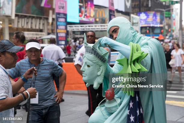 Cosplayer takes off his Statue of Liberty mask amid high temperature at Times Square on July 27, 2022 in New York City.