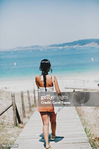 rear view young latina in summer dress walking to beach with reusable cotton tote bag - boodschappentas schoudertas stockfoto's en -beelden