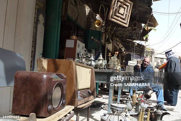 Man sits at his kiosk in the 300-year-old Souk al-Haraj in Midan Square in old Baghdad on March 11 where traders specialize in fixing old radios and...