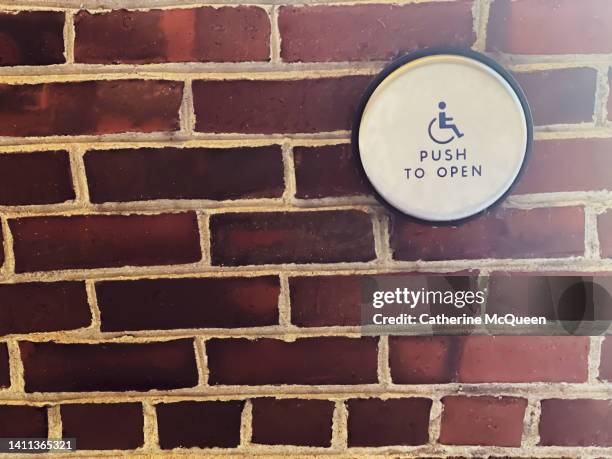 wheelchair accessibility sign: “push to open” door button on brick wall - ada stock-fotos und bilder