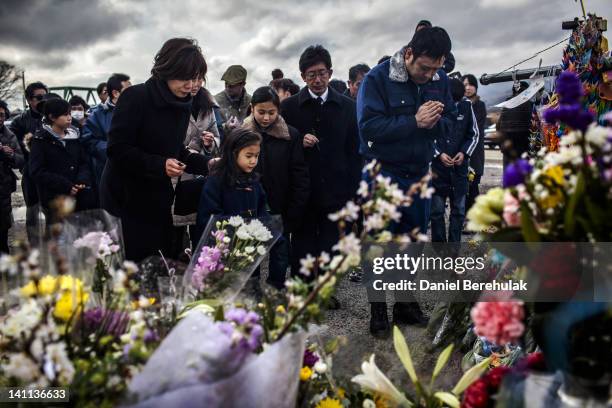 Family pay their respects to victims of the last year's tsunami at a memorial, at the Okawa Elementary School, where 74 children were killed and 4...