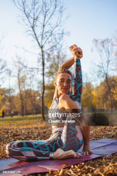 femme pratiquant le yoga dans le parc, assumant la pose du cadran solaire 1 les yeux fermés - human arm photos et images de collection