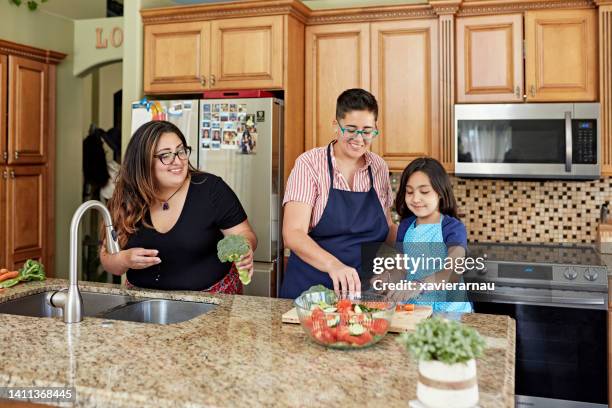 mid adult women and young daughter cooking together - young family in kitchen stock pictures, royalty-free photos & images