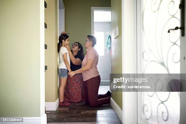 lesbian parents measuring daughter’s height - growth chart stock pictures, royalty-free photos & images