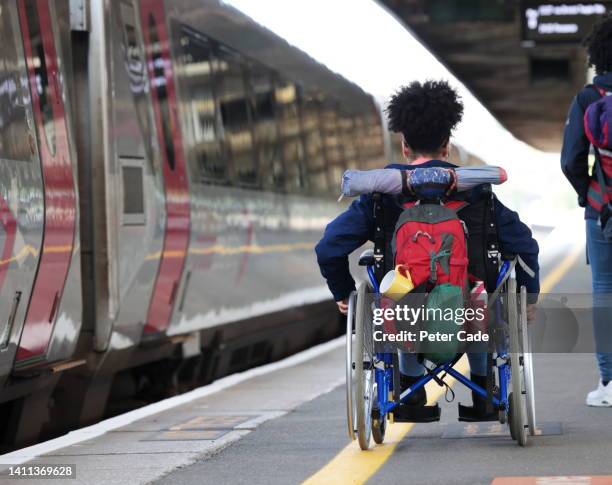 disabled young woman in wheelchair at station - wheelchair access stock pictures, royalty-free photos & images