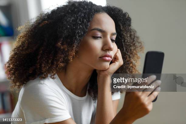 woman looking at mobile phone screen - 煩擾 個照片及圖片檔
