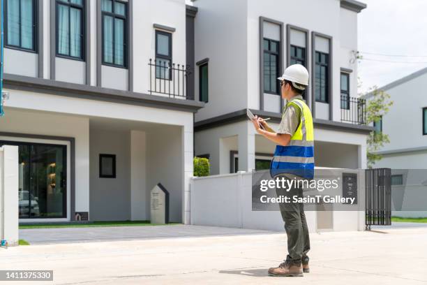 man inspecting house exterior with tablet - quality control inspectors stock pictures, royalty-free photos & images