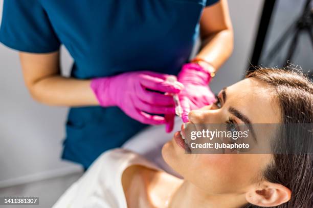 kosmetikerin macht eine injektion von hyaluronsäure in eine schöne lippen - lippen stock-fotos und bilder