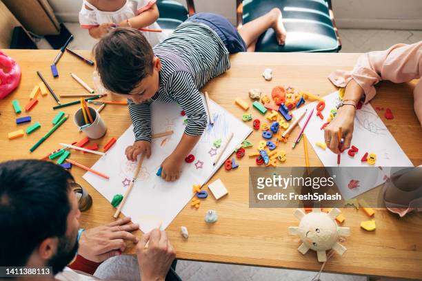 boy drawing and colouring with his father - craft table stock pictures, royalty-free photos & images