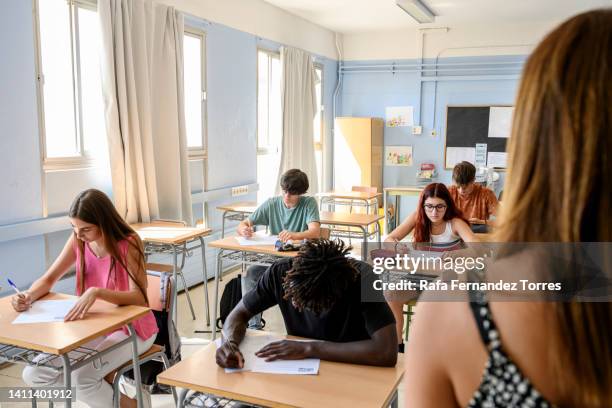 teacher watching over teenagers in classroom - overworked teacher stock pictures, royalty-free photos & images