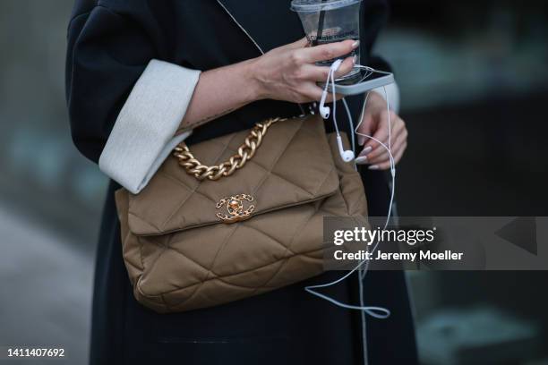 Maria Barteczko is seen wearing black long oversized coat, black long oversized shirt dress and black baggy pants from WENDYKEI, brown canvas quilted...