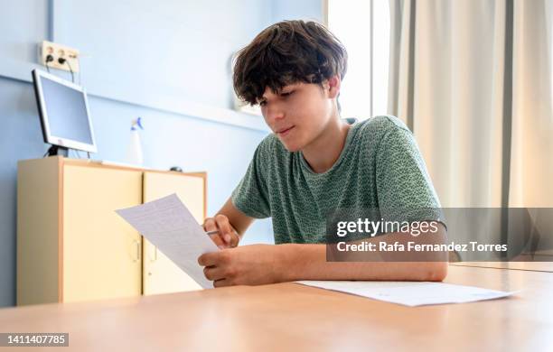 male teen student holding a paper while sitting at classroom - boy in briefs photos et images de collection