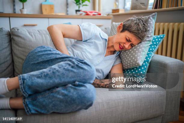 woman suffering from stomach cramps - endometriosis stock pictures, royalty-free photos & images