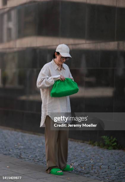 Maria Barteczko is seen wearing linen button down oversized Arket shirt, brown wide leg Zara pants, abeige canvas baseball Arket cap, green terry...
