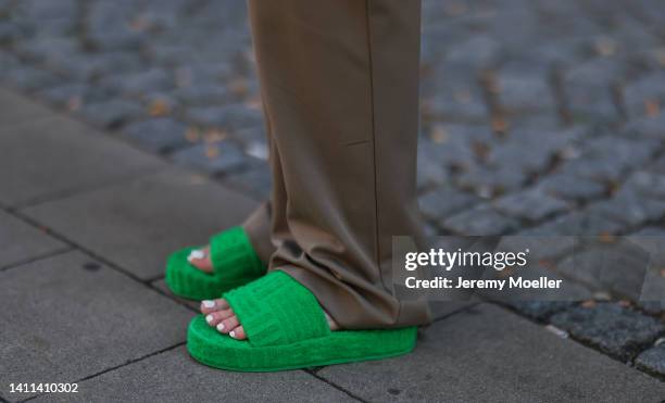 Maria Barteczko is seen wearing linen button down oversized Arket shirt, brown wide leg Zara pants, green terry pouch Bottega Veneta bag and green...