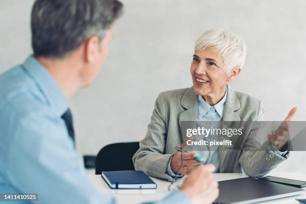 senior businesswoman talking to a colleague in the office - role model stock pictures, royalty-free photos & images