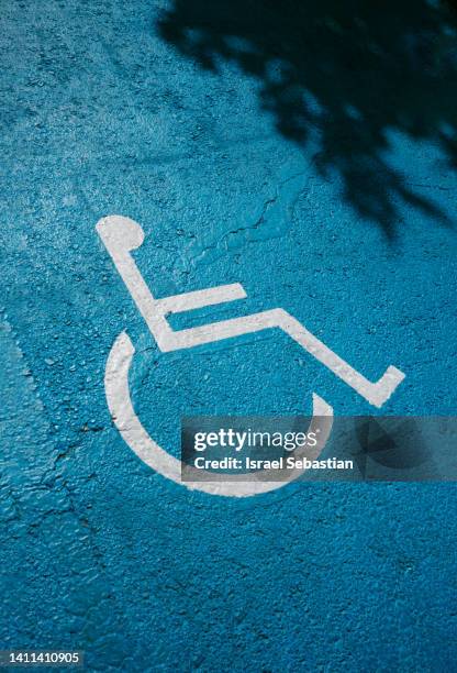 handicapped parking sign painted on the ground in a public parking lot in blue color. - simbolo internazionale di accesso foto e immagini stock
