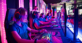 Diverse blue pro gamer team with female players competing at video game eSport championship with a coach