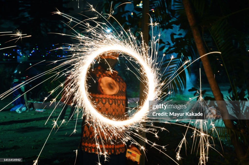 Long exposure shot of man enjoying lit sparkler on Diwali night