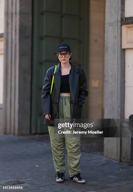 Maria Barteczko is seen wearing a Balenciaga black logo baseball cap, a Zara black vegan leather blazer, Asos black cropped top, Source Unknown green...