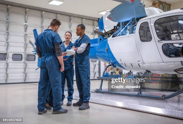 gruppe von mechanikern diskutiert in der nähe des hubschraubers - aircraft mechanic stock-fotos und bilder