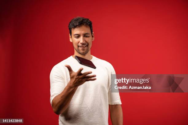 casually dressed asian man using his smartphone in studio - throwing phone stock pictures, royalty-free photos & images