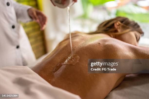 masseuse pouring oil on customer's back - deep relaxation stock pictures, royalty-free photos & images