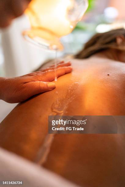 masseuse pouring oil on customer's back - images of brazilian wax 個照片及圖片檔