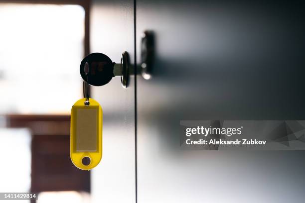 a closed metal locker with a key and a key tag in the office. the lock of the filing cabinet with a key. security and security system in a public institution. individual confidential locker, luggage storage in a hostel or coworking. - georgia steel fotografías e imágenes de stock