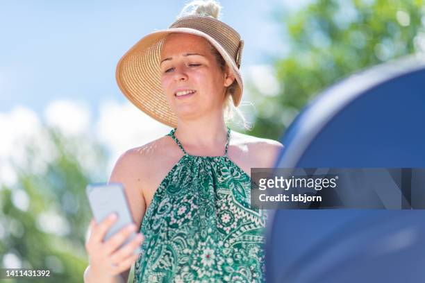 mother pushing baby stroller and using mobile phone - mother media call stock pictures, royalty-free photos & images