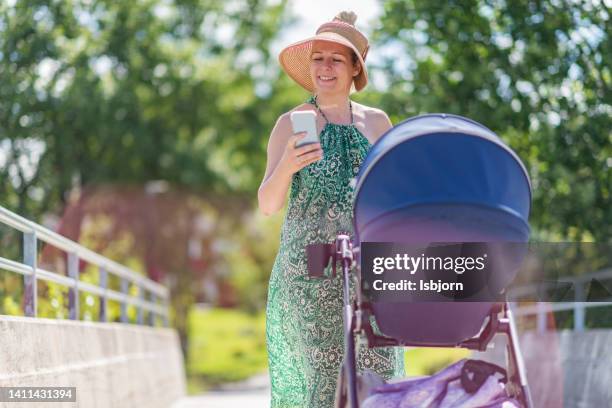 busy mother pushing baby stroller and using mobile phone - mother media call stock pictures, royalty-free photos & images