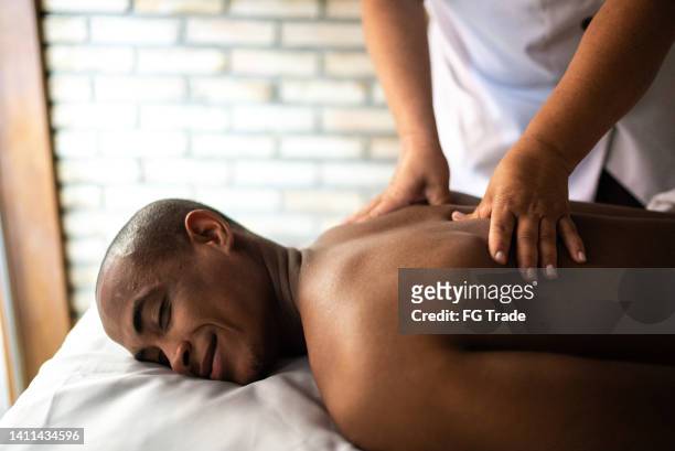 joven recibiendo masaje en un spa de belleza - black massage therapist fotografías e imágenes de stock
