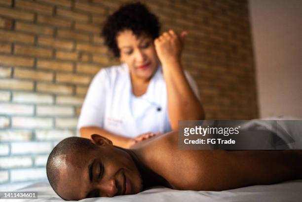 joven recibiendo masaje en un spa de belleza - black massage therapist fotografías e imágenes de stock