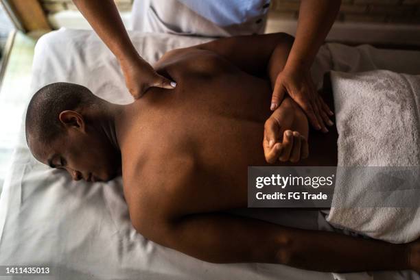 joven recibiendo masaje en un spa de belleza - black massage therapist fotografías e imágenes de stock