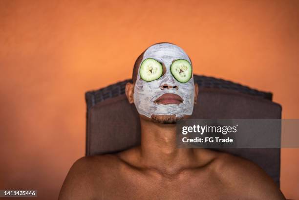 man in a spa with facial mask and cucumbers covering eyes - men facial stock pictures, royalty-free photos & images